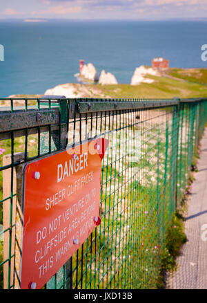 Danger sheer cliff faces - warning sign attached to a fence at the Needles on the Isle of Wight, UK. Stock Photo