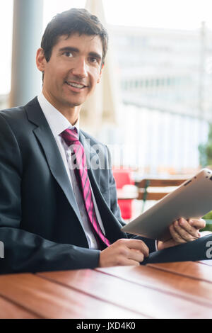 Young man wearing business suit while using a tablet PC during b Stock Photo