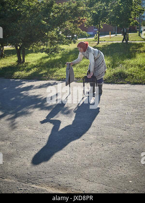 Poor old woman walking with a bent back around the city and begging. Filmed in Belarus. Stock Photo