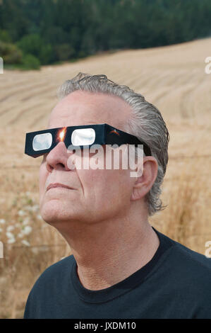 Man viewing solar eclipse with solar glasses in country field Stock Photo