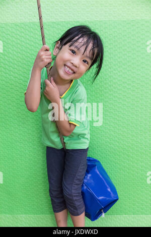 Asian Chinese little girl riding on a rope in the gym class Stock Photo