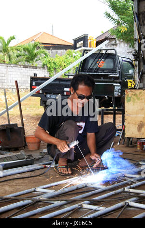 Kuta/Bali - September 13, 2016: Male welder/fabricator welding metalwork in workshop Stock Photo