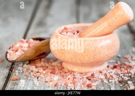 Pink himalayan salt in wooden scoop and rose quarz mortare on old wooden background Stock Photo