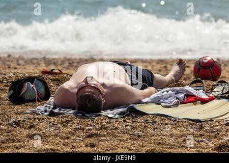 West Bay, Dorset, UK. 15th August, 2017. UK Weather: Locals and holidaymakers enjoy a hot sunny afternoon sunbathing and swimming at the seaside resort of West Bay. Photograph Credit: Guy Corbishley/Alamy Live News Stock Photo