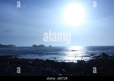 British Channel Islands. Alderney. View of coast and distant Fort Clonque in bright early evening sun. Stock Photo