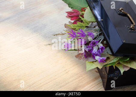 Autumn composition - a vintage box with an open lid, under which autumn leaves and wildflowers. Wooden background. Side view. Copy space Stock Photo