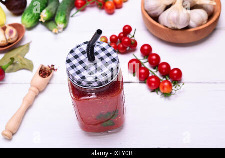 Freshly squeezed tomato juice in a glass jar with a straw on a white wooden table, top view Stock Photo