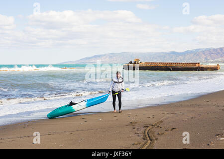 young man carrying his kayak into the water Stock Photo