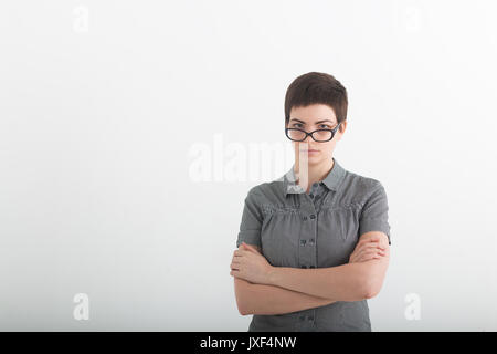 Confident business expert. Beautiful young woman in smart casual wear keeping arms crossed and looking serious while standing against grey background. Stock Photo