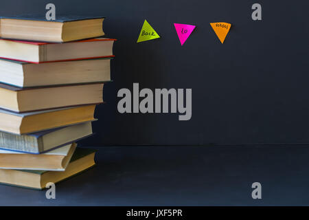 Close-up of a stack of books in hard bindings on black background. Place for text, concept of starting school, back to school, education Stock Photo