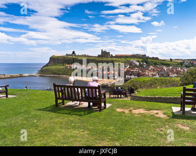 dh Town harbour viewpoint WHITBY NORTH YORKSHIRE UK People couple sitting relaxing overlooking abbey summer tourism holiday view from west cliff Stock Photo