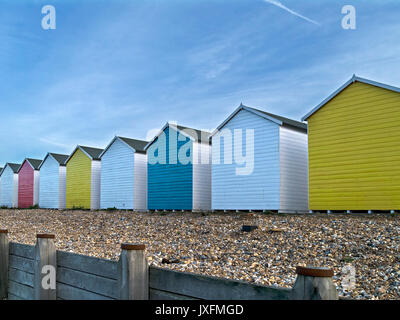 Row of brightly painted colourful wooden beach huts on Eastbourne shingle beach with blue sky above, Eastbourne, East Sussex, England, UK Stock Photo