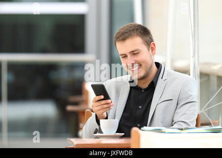 Happy executive using mobile phone sitting in a coffee shop Stock Photo