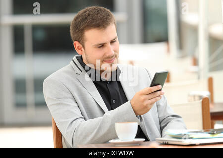 Serious executive using a mobile phone sitting in a coffee shop Stock Photo