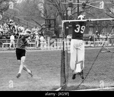 Lacrosse Action shot taken during an unidentified lacrosse match at Homewood campus, A member of the opposing team endeavors to make a goal, while the goalie seems to catch the ball, 1950. Stock Photo