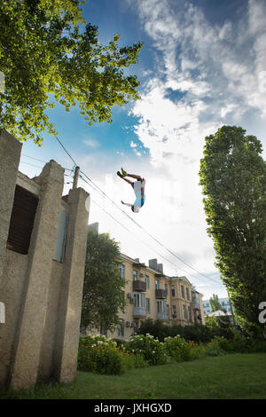 City parkour. The guy does the opposite somersault. Shooting from a low angle. Agility, adrenaline and extreme. Stock Photo