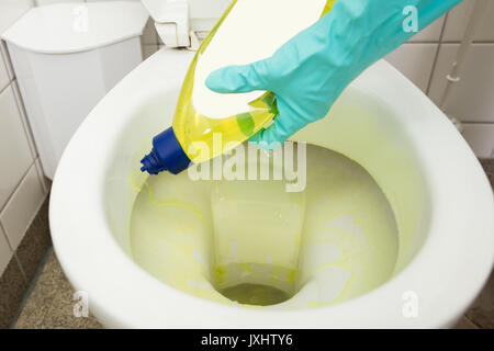 Close-up Of Person Hand Cleaning Toilet Bowl Using Detergent At Home Stock Photo