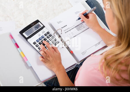 High Angle View Of Woman Calculating Budget Using Calculator At Home Stock Photo