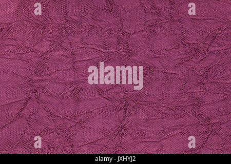 Dark purple wavy background from a textile material. Fabric with fold texture closeup. Creased shiny magenta cloth. Stock Photo