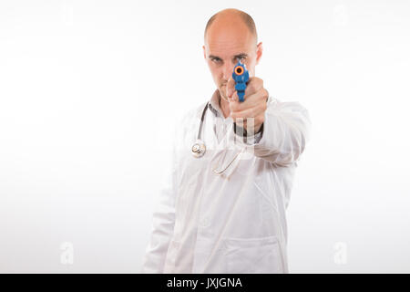 Doctor wearing a lab coat and stethoscope pointing a toy gun at the camera with a determined expression over white Stock Photo