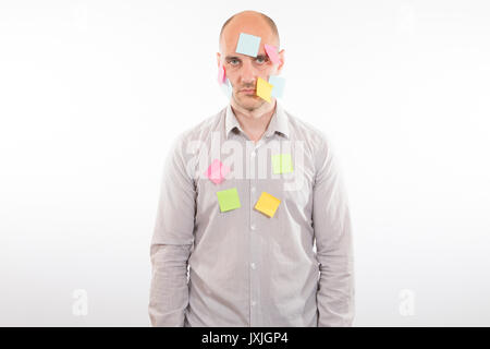 Serious man standing against white background covered with sticky notes Stock Photo