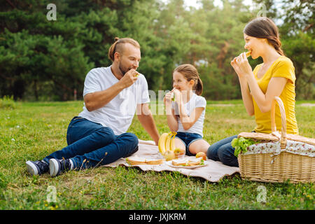 Happy lovely family eating sandwiches on picnic Stock Photo