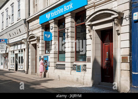 Woman person using ATM outside Yorkshire Bank branch exterior Scarborough North Yorkshire England UK United Kingdom GB Great Britain Stock Photo