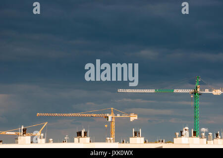 three different cranes in perspective against storm sky Stock Photo