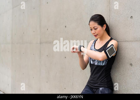 beautiful professional female athlete wearing smart watch using sports app record personal heart rate and grades ready for running training on gray ba Stock Photo