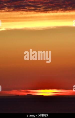 Sunset with island and ship on horizon taken from Abereiddy Bay in West Wales, UK Stock Photo