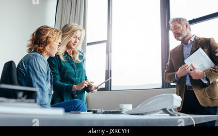 business woman explaining something to female coworker with a digital tablet in office. business people in office with digital tablet. Stock Photo
