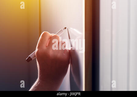 School teacher writing on classroom whiteboard during the lecture, selective focus Stock Photo