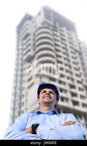 Engineer working on a building site wearing a protective helmet standing on the building background. Engineering and architecture concept. Stock Photo