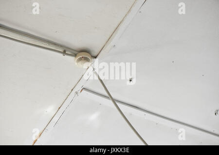 Smoke detector of fire alarm on white wooden ceiling. Stock Photo