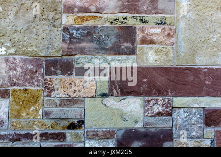 A wall tiled and bricked in a random fashion with different  sizes and colours Stock Photo