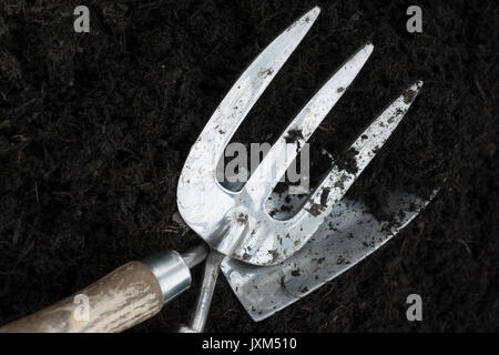 Hand Trowel and Hand Fork in soil Stock Photo