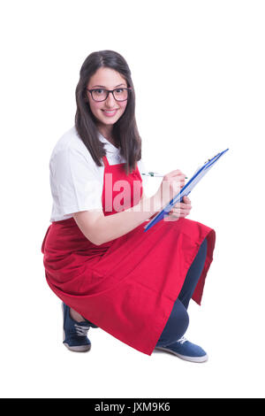 Beautiful brunette seller taking inventory in the supermarket and smiling confident Stock Photo