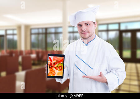 Cook man showing digital tablet with fresh ingredients promoting organic food in restaurant Stock Photo