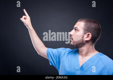Man medical nurse wearing scrubs using invisible touchscreen on black background Stock Photo