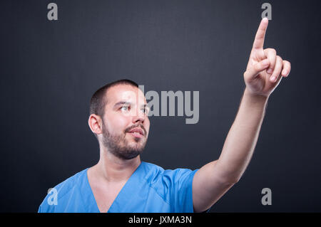 Man medical nurse wearing scrubs using invisible touchscreen on black background Stock Photo