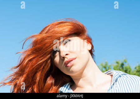 Beautiful portrait of redhead girl standing outside in warm sunny day Stock Photo