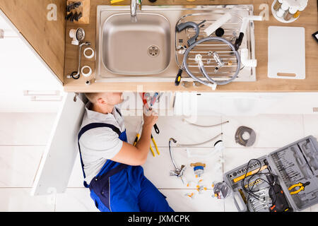 High Angle View Of Male Plumber In Overall Fixing Sink Pipe Stock Photo