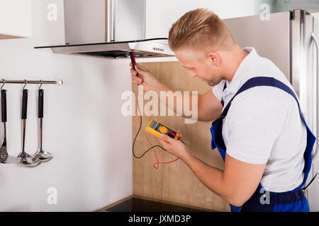 Young Male Technician Checking Kitchen Extractor Filter With Digital Multimeter Stock Photo