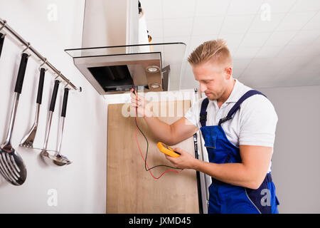 Young Male Technician Checking Kitchen Extractor Filter With Digital Multimeter Stock Photo