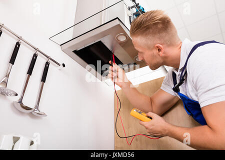 Young Male Technician Checking Kitchen Extractor Filter With Digital Multimeter Stock Photo