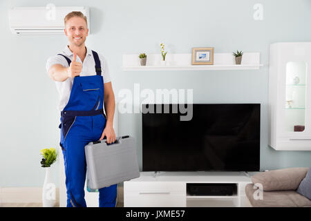 Smiling Young Male Technician Gesturing Thumbs Up Stock Photo