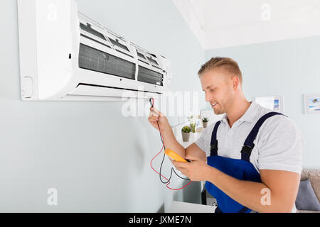 Male Electrician Checking Air Conditioner With Digital Multimeter Stock Photo