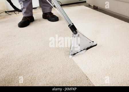 Close-up Of A Person Cleaning Carpet With Vacuum Cleaner Stock Photo