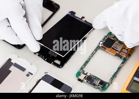 Close-up Of Person's Hand Fixing Damaged Screen On Mobile Phone Stock Photo