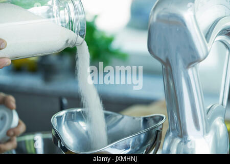 Person pouring ingredients into vintage scales, close-up Stock Photo